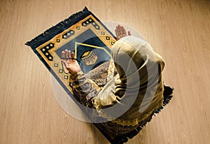 Muslim woman praying for Allah muslim god at room near window. Hands of muslim woman on the carpet praying in traditional wearing