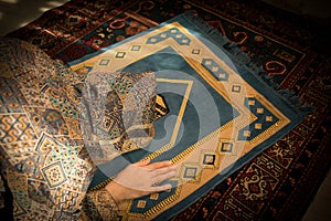 Muslim woman praying for Allah muslim god at room near window. Hands of muslim woman on the carpet praying in traditional wearing