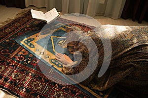 Muslim woman praying for Allah muslim god at room near window. Hands of muslim woman on the carpet praying in traditional wearing