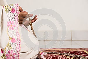 Muslim woman praying close up image of hands as she holds prayer beads,tasbih