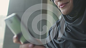 Muslim woman reading message from boyfriend on phone, acquainting on dating site