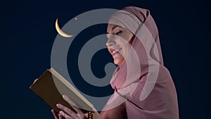 A Muslim woman reads the Quran against the background of a the moon and star