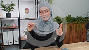 Muslim woman real estate agent showing keys of new home house apartment, buying or renting property