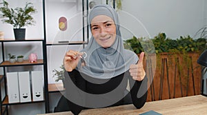 Muslim woman real estate agent showing keys of new home house apartment, buying or renting property