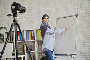 Muslim woman recording a video as she explaining something on a whiteboard
