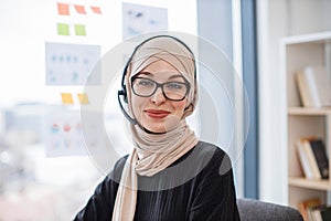 Muslim woman in scarf posing with headset in office interior
