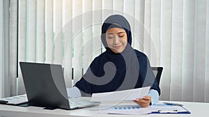 Muslim woman sitting happily at the office