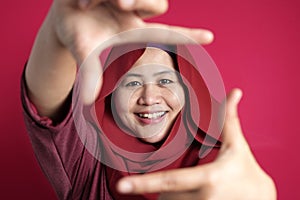 Muslim woman smiling at camera while framing her face with hands