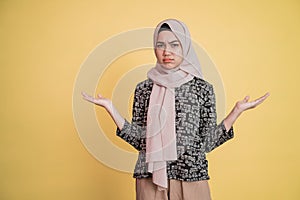 Muslim woman with sullen facial expression and sideways hand gesture helplessly