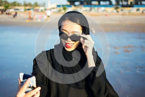 Muslim woman taking selfie on the beach