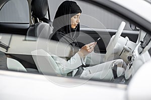 Muslim woman talks on phone while driving a car