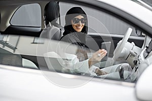 Muslim woman talks on phone while driving a car