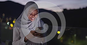 Muslim woman texting on smartphone with bokeh city light in background