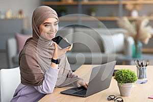 Muslim woman using voice assistant on cellphone