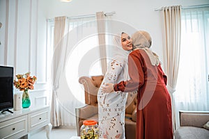 Muslim woman in veil visiting and hugging while celebrating Eid