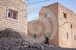 Muslim woman walking between ruined buildings in Marocco