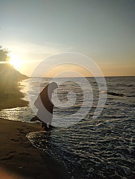 A muslim woman wearig burka on the beach during sunset