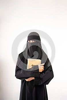 muslim woman wearing a black hijab and long dress holding al qur'an