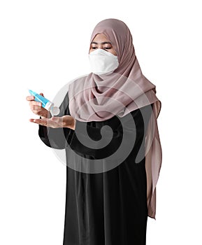 Muslim woman wearing a surgical mask washing hands with alcohol gel on white background. Covid-19 coronavirus concept