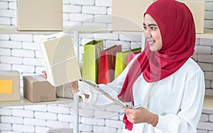 Muslim woman who owns a business, She inspects the product before sending the parcel for delivery to customers online.