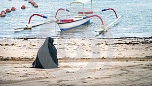 Muslim women in Abaya Niqab sitting and relaxing the beach at the sea. Nusa Dua, Bali