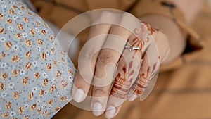 A Muslim women with henna tattoo hijab touching cap with her hands