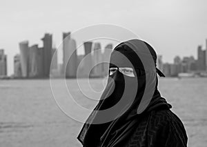 A muslim women with niqab near the Doha city skyline