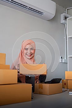 Muslim women selling online at home with box. Selling online with box to accept order from customer. SME business idea