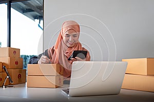 Muslim women selling online at home with box. Selling online with box to accept order from customer. SME business idea