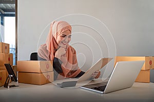 Muslim women selling online at home with box. Selling online with box to accept order from customer. SME business idea