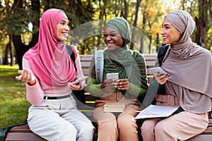 Muslim Women Using Phones Talking And Having Fun In Park
