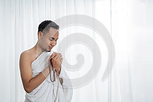 Muslim young man praying using tasbih