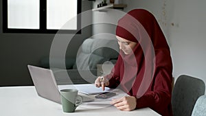 Muslim young woman in hijab managing home finance.