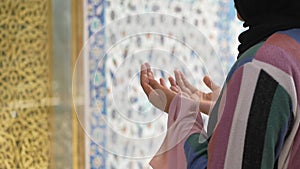 Muslim young woman in hijab is praying in mosque.