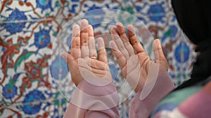 Muslim young woman in hijab is praying in mosque.