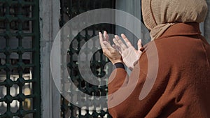 Muslim young woman in hijab is praying in mosque.