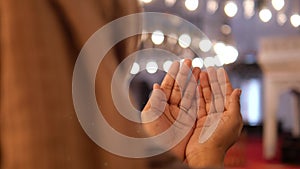 Muslim young woman in hijab is praying in mosque.