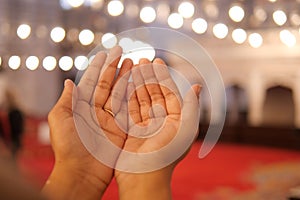 Muslim young woman in hijab is praying in mosque.