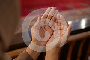 Muslim young woman in hijab is praying in mosque.