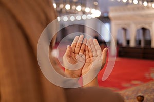 Muslim young woman in hijab is praying in mosque.