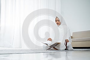 Muslim young woman praying in white traditional clothes