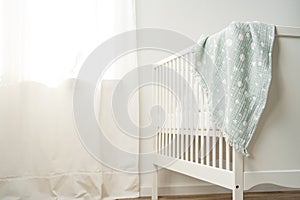 Muslin baby blanket hanging on child's bed in nursing room