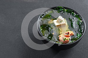Muso soup with salmon in a black bowl on a black background. Asian food on a dark background photo