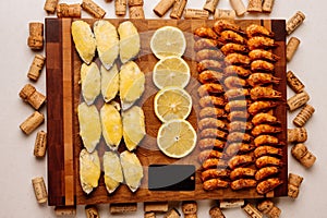 Mussels baked with cheese sauce and sliced lemon and fried shrimps on wooden cutting board with card and wine corks