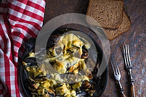 Mussels with cheese sauce in a frying pan, napkin in a red cage close-up