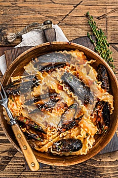 Mussels and clams Mafaldine pasta with tomato sauce in a rustic wooden plate. Wooden background. Top view