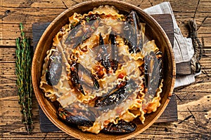 Mussels and clams Mafaldine pasta with tomato sauce in a rustic wooden plate. Wooden background. Top view