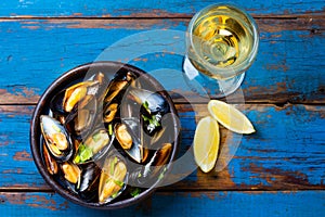 Mussels in clay bowl, glass of white wine and lemon photo