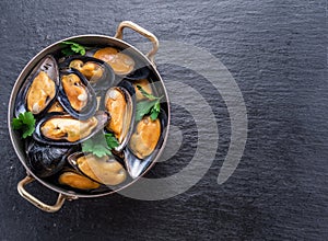 Mussels in copper pan on the graphite background