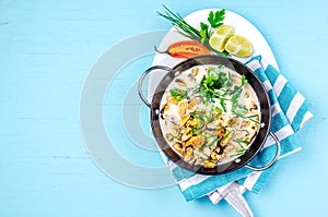 Mussels in creamy milk sauce with aromatic herbs and lemon. Top view Blue background. Top view